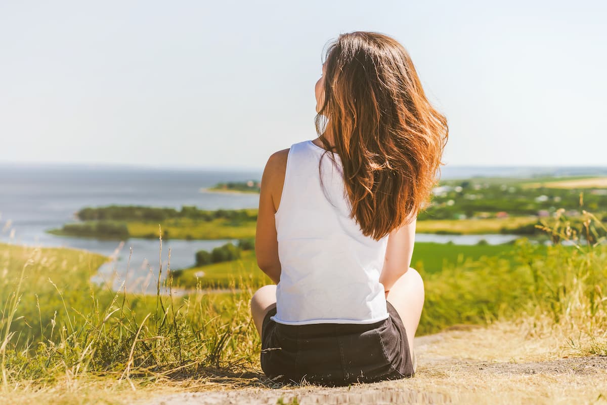 Woman with long hair sitting on a shoreline