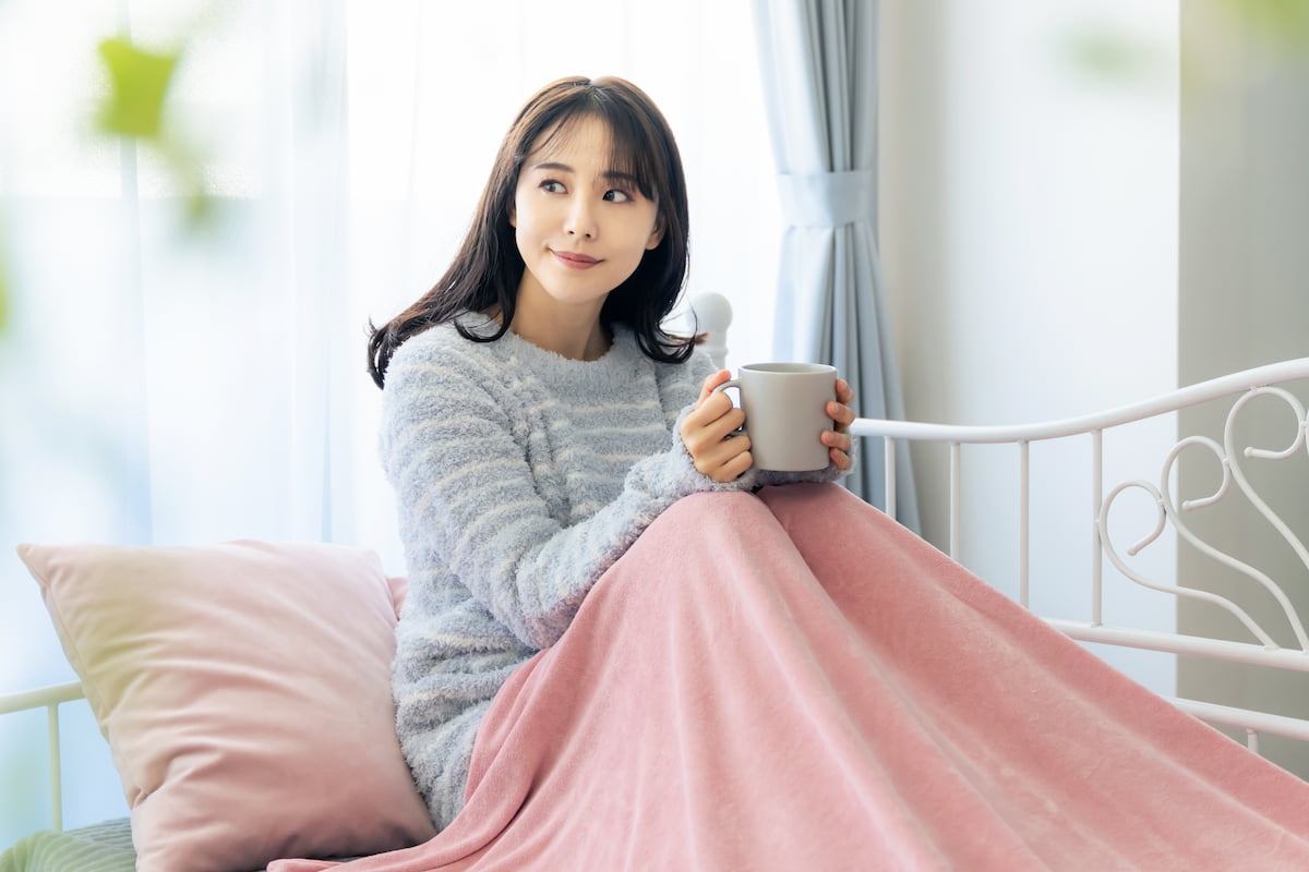 woman sitting under a blanket and holding a coffee cup