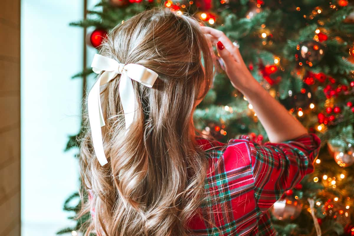 A  woman with a hair bow facing a Christmas tree